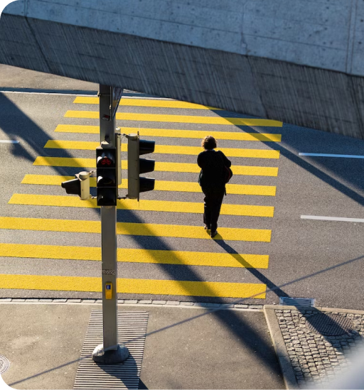 A view above a street showing a single person crossing an intersection on a crosswalk.